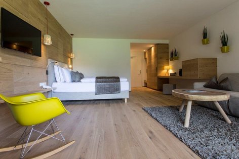 Schlafzimmer mit gelbem Schaukelstuhl und weißen Landhausdielen