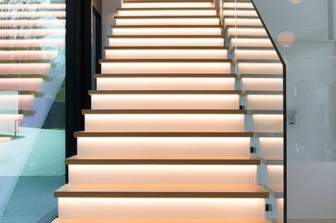 Top view of oak parquet steps on a modern staircase with glass banisters