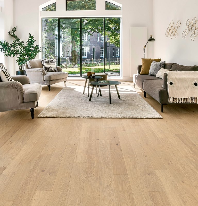 Parkett Landhausdiele Eiche Natur Nebla Geräumiges Wohnzimmer mit hellem Eichenparkett, modernen Möbeln, großer Fensterfront und Industriedeko.