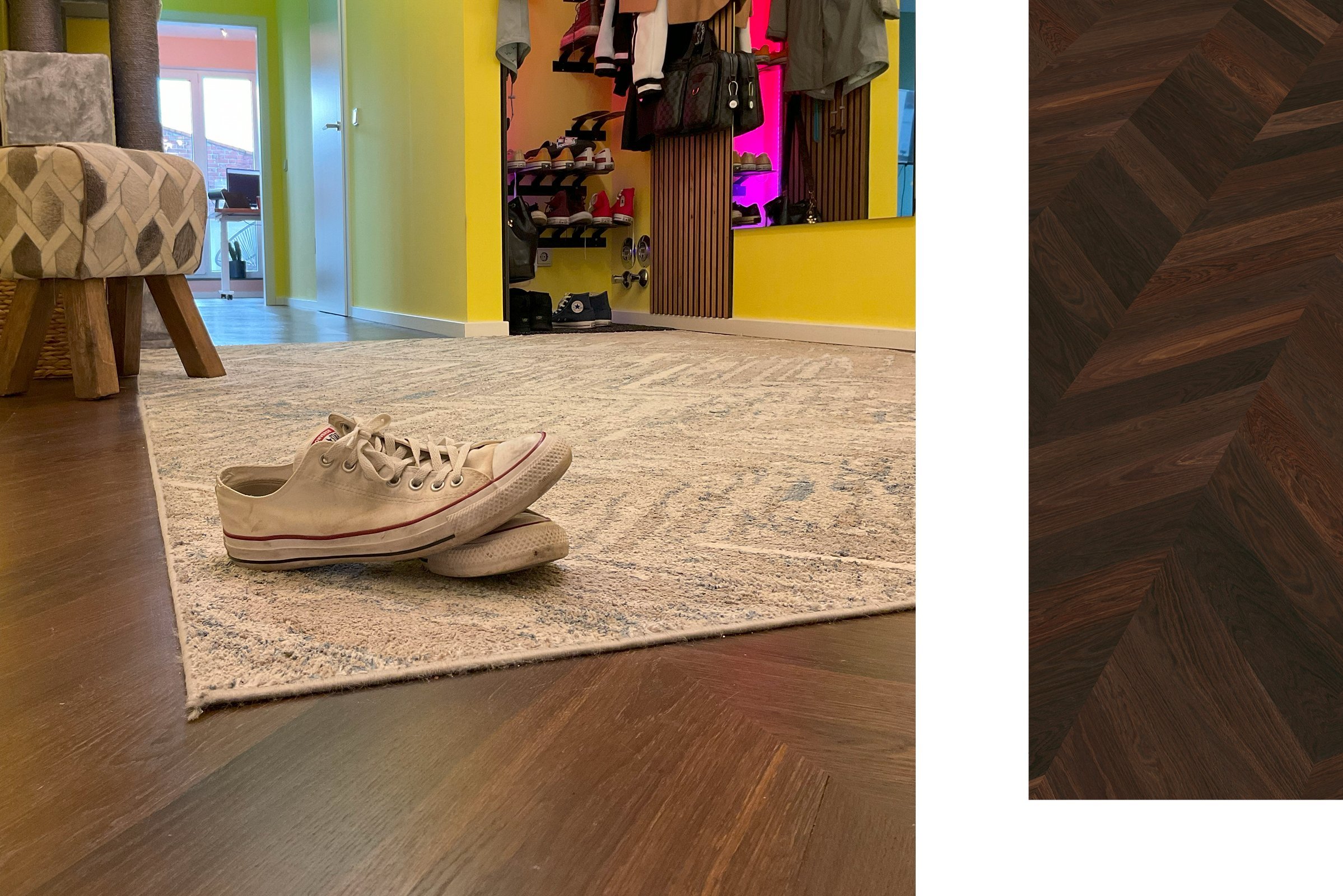 Flur mit bunter Wandfarbe und dunklem französischem Fischgrätparkett, darauf ein hochwertiger Teppich und Converse-Schuhe.