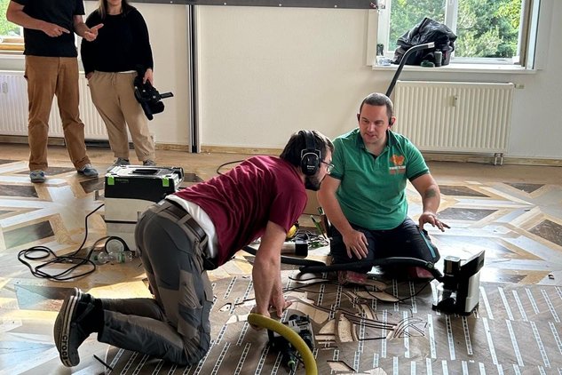 Parkettleger auf dem Boden welche Parkett bearbeiten und sich absprechen