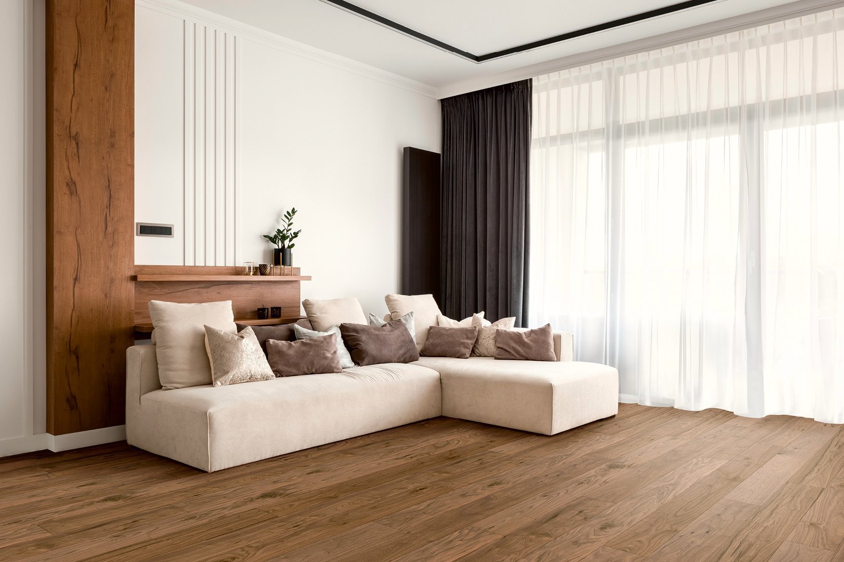 Living room with couch and curtains in earthy colors. There is walnut parquet flooring on the floor and a walnut wooden element with a shelf on the wall
