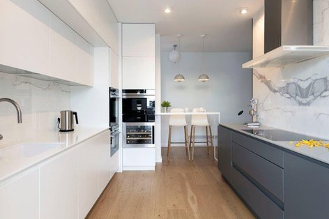 Weiße und graue Küche mit Marmorrückwand und Holzboden