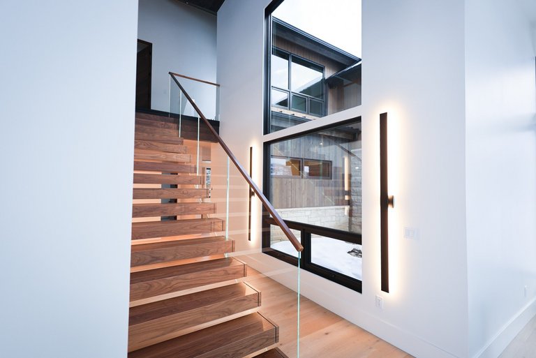 Treppenaufgang mit Parkett und Beleuchtung sowie großen schwarzen Fenstern
