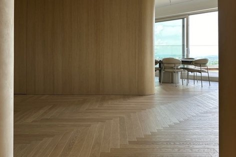 Heller Wohnraum mit modernem Fischgrätparkett in Eiche weiß und Holzwand