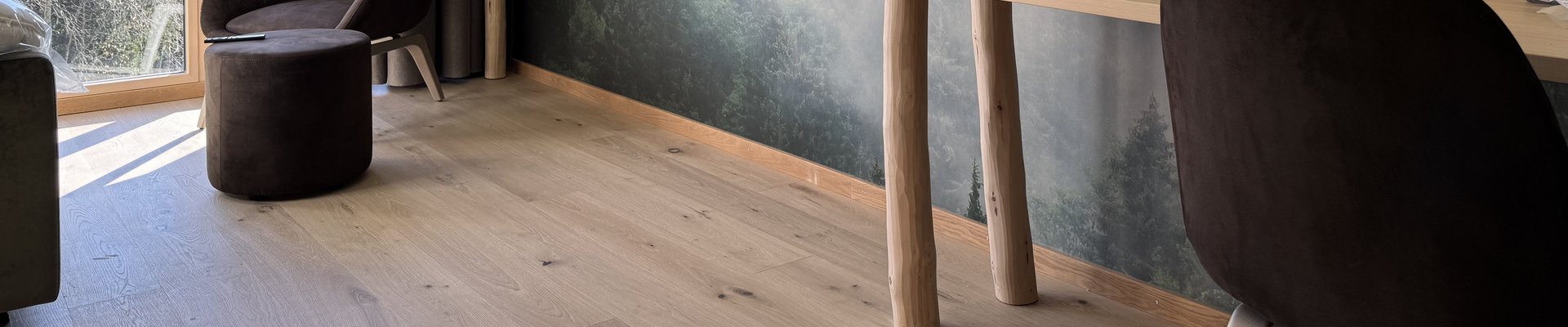 Natürliches Hotelzimmer mit Eichenparkett, sanft grüner Waldtapete und natürlichem Interior.