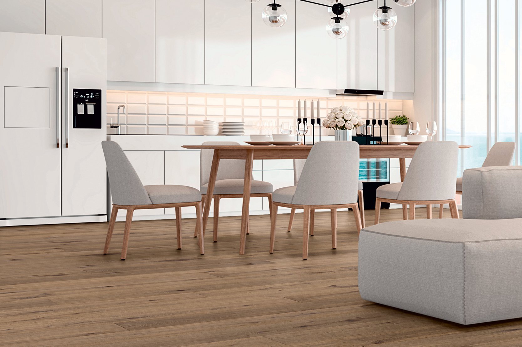 Kitchen with white fronts up to the ceiling, in front of it a wooden dining table with gray chairs and a gray couch. The room is laid with high-quality oak parquet flooring in a country house plank look.