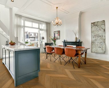 Esszimmer im klassischen, eleganten Stil mit französischem Fischgrät-Parkett aus gedämpfter Eiche. Die Möbel und Dekoration, darunter ein Kronleuchter, ergänzen den klassischen Look des Raumes.
