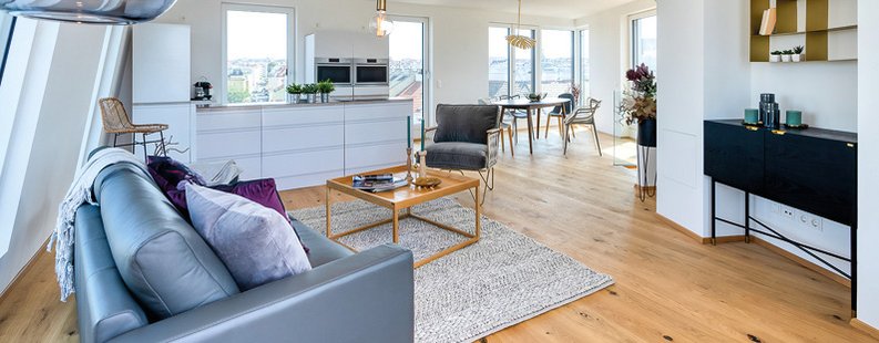 Wohnzimmer, Küche und Esszimmer einer Wohnung mit Parkett aus rustikaler Eiche, kombiniert mit moderner Einrichtung.