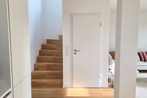 Holztreppe in Staboptik führt in den Eingangsbereich mit hellen Eichendielen.
