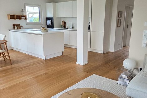 Heller Wohn-Essbereich mit weißer Küche und Eichenparkett als Landhausdiele, natürlicher Parkettboden in modernem Holzboden-Design.