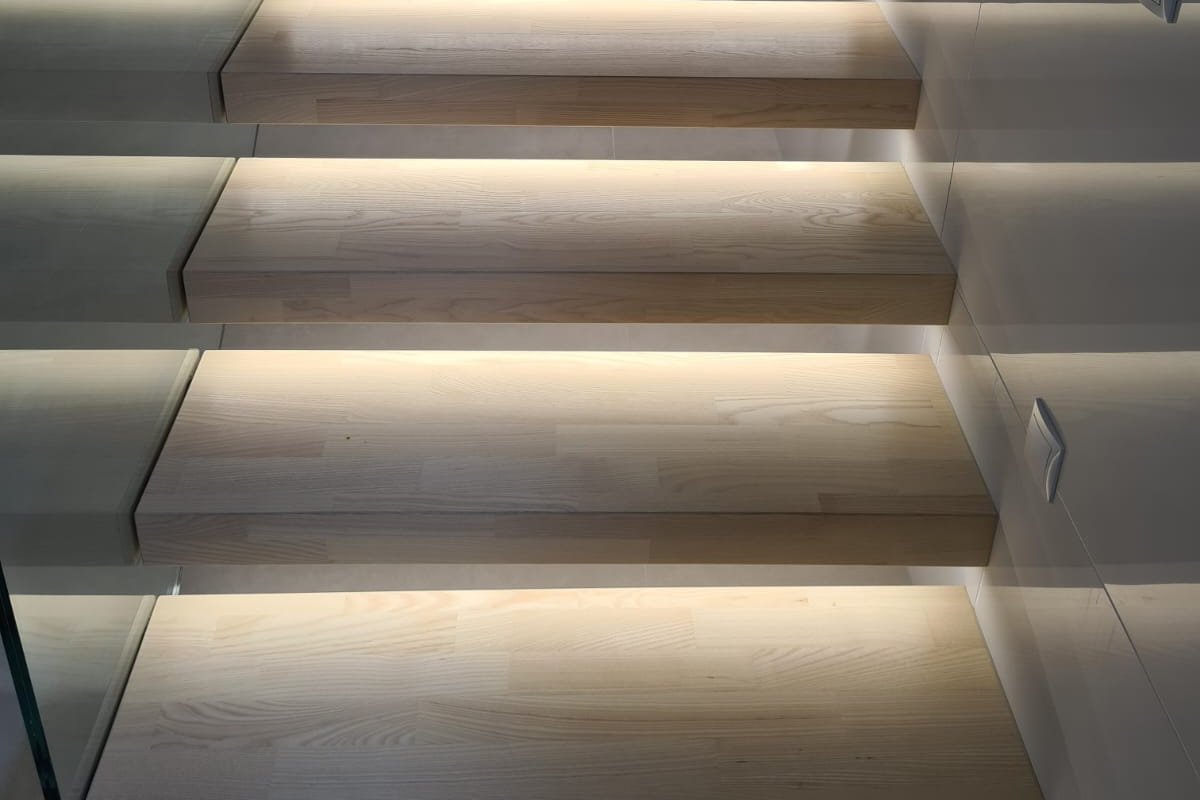 [Translate to EN:] Treppe beleuchtet aus Eschenparkett