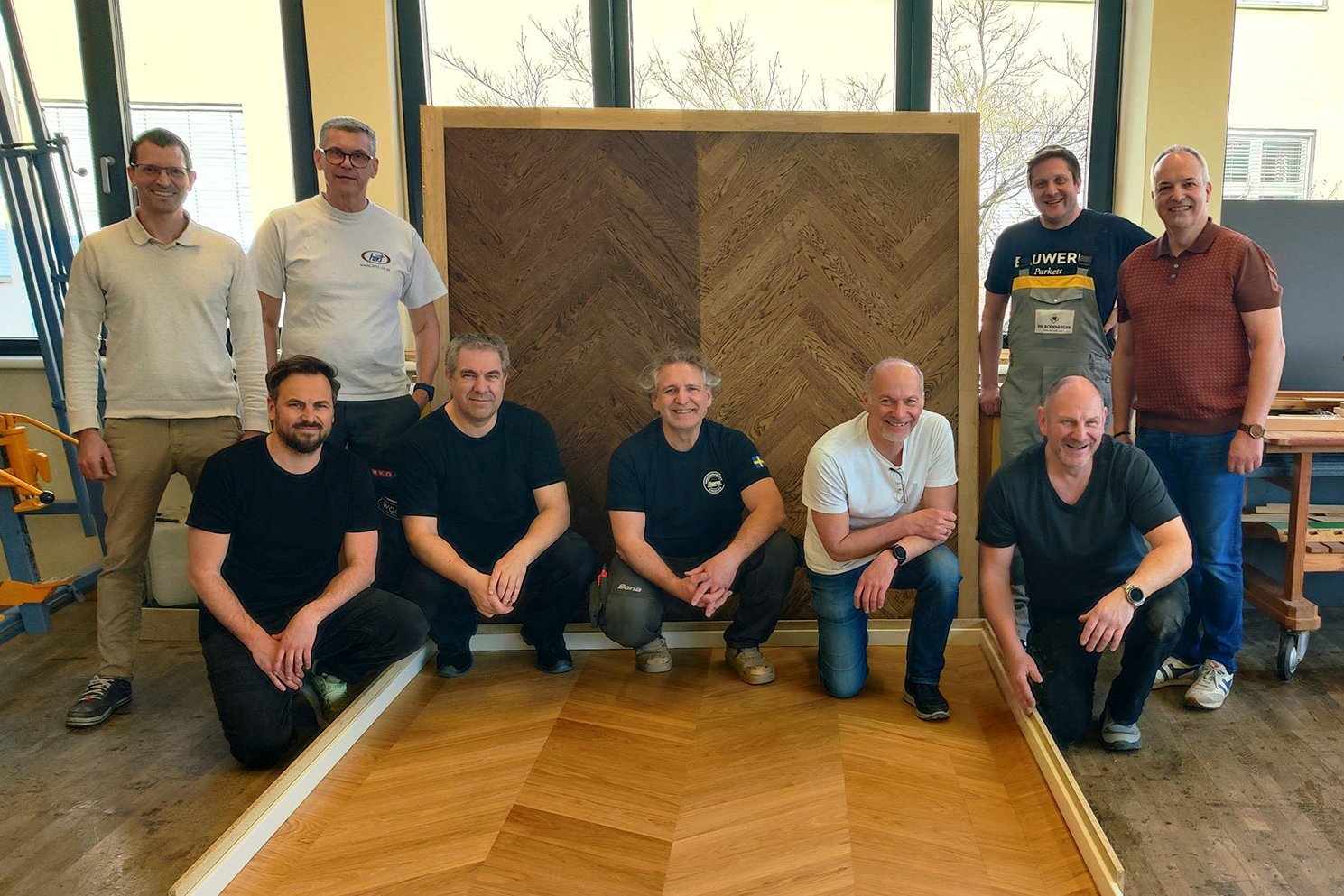 Gruppenfoto mit Männern und zwei Platten mit Fischgrät Parkett der von diesen bearbeitet wurde