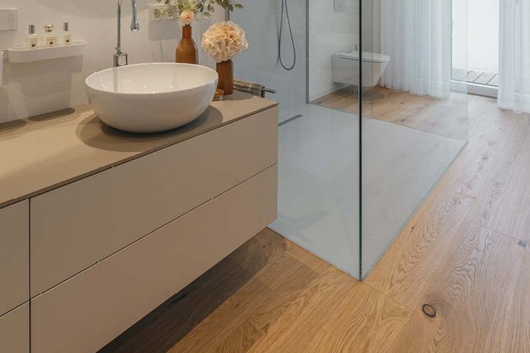 Bathroom with oak parquet flooring around the shower and a beige washbasin