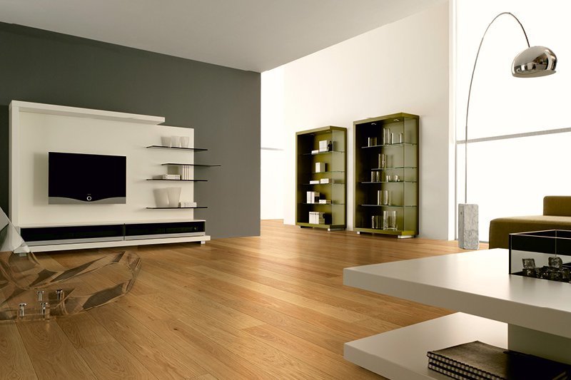 Moderner Wohnraum mit Landhausdielen aus Eiche. Die Wand ist dunkelgrau gestrichen, während die Möbel in Weiß und Grün gehalten sind. Ein transparenter Sessel und eine silberne Stehleuchte ergänzen den Raum.