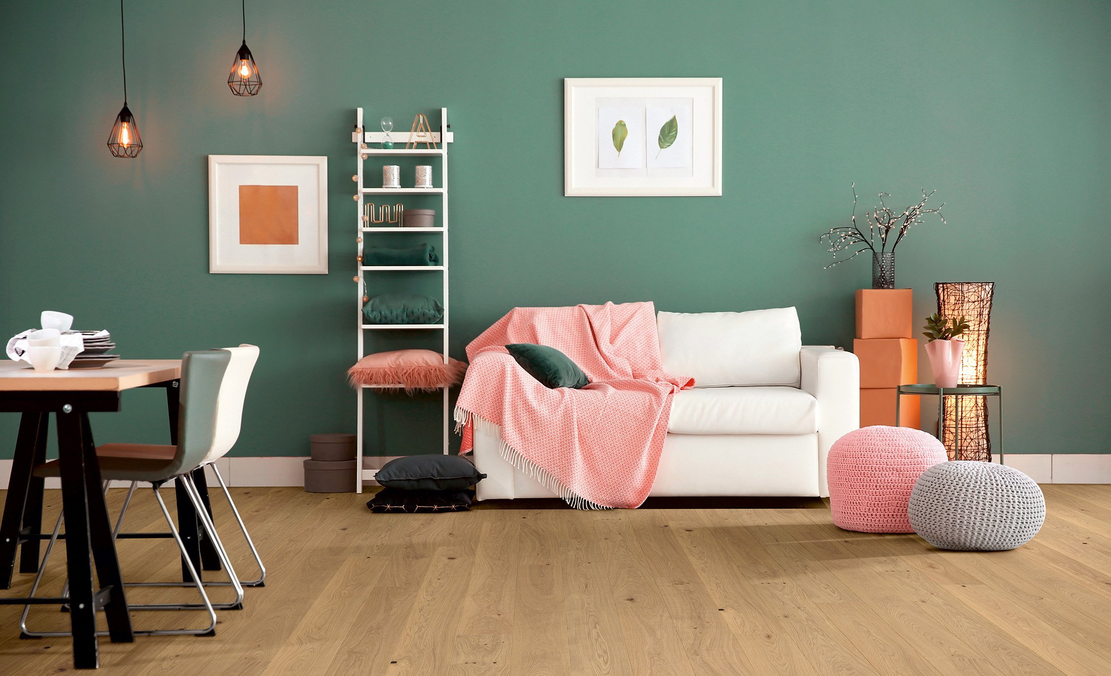Landhausdiele Eiche astig Perla „Weiß geöltes Eichenparkett in einem Wohnzimmer mit petrolfarbener Wand, weißem Sofa und Esstisch mit Geschirr.