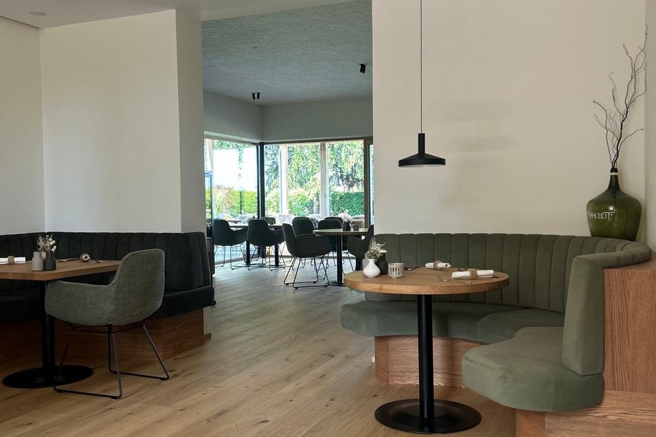 Großzügiger Gastraum mit Landhausdielen Eiche rustikal, puristischem Interieur in grün und schwarz