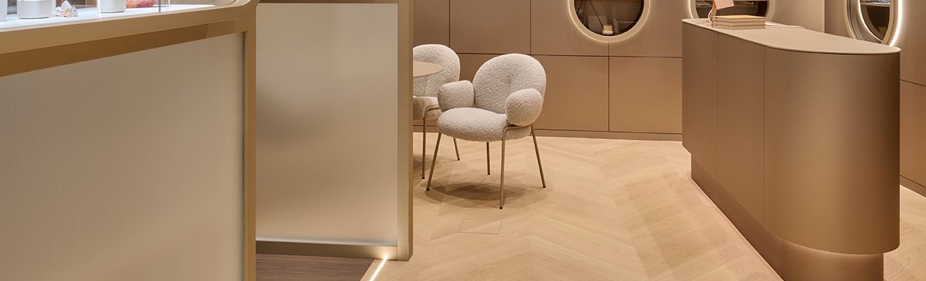 Uhrenboutique mit luxuriösem Interior in Creme und Gold. Am Boden liegt hochwertiges Französisches Fischgrät Parkett in weiß geölter Eiche.