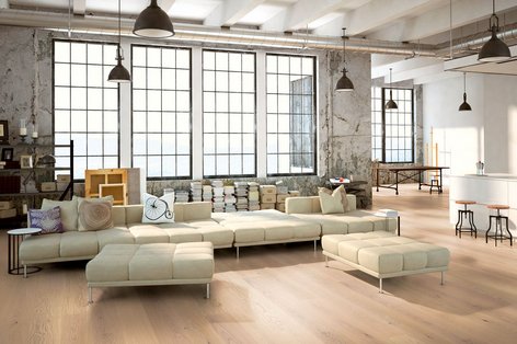 Loft mit heller Couch im Industrialstil und Parkett