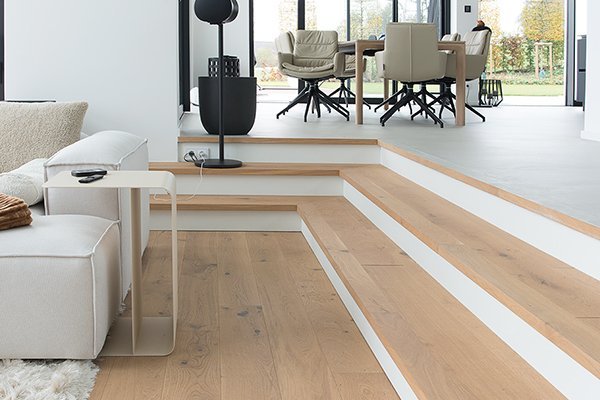 Transition with 2 steps into the living room with a wooden floor in white oak
