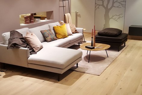 Hellbeiges Sofa mit rosa Wand und Parkettboden