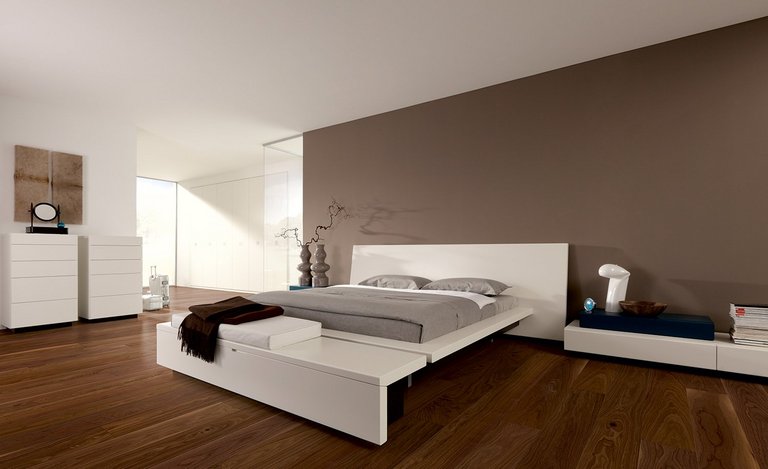 Schlafzimmer mit dunklem Nussbaum Holzboden, weißen Möbeln und Wand in Graubraun mit Dekoration in Erdtönen.