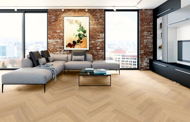 Modernes Loft mit Fischgrät-Parkett in Eiche weiß, Backsteinmauer und hellgrauem Sofa mit schwarzen Metallbeine