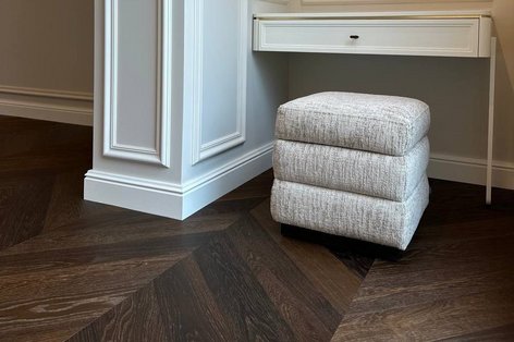 Dunkles Französisches Fischrätparkett mit Stuckwänden und hellem Hocker