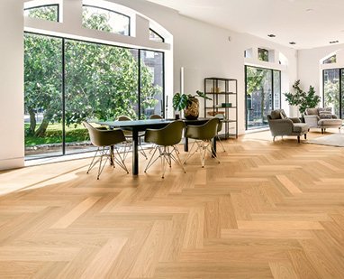 Loftartiger Wohnraum mit hochwertigem Fischgrät-Parkett aus Eiche. Das Interieur in Oliv- und Schwarztönen wird durch bodentiefe Fenster erhellt.