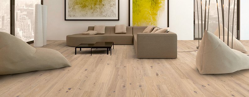 Weitläufiges Wohnzimmer mit Parkett Eiche rusikal in weiß und naturfarbenen Sitzelementen. an der Wand hängen sehr große Bilder in grün und gelb.