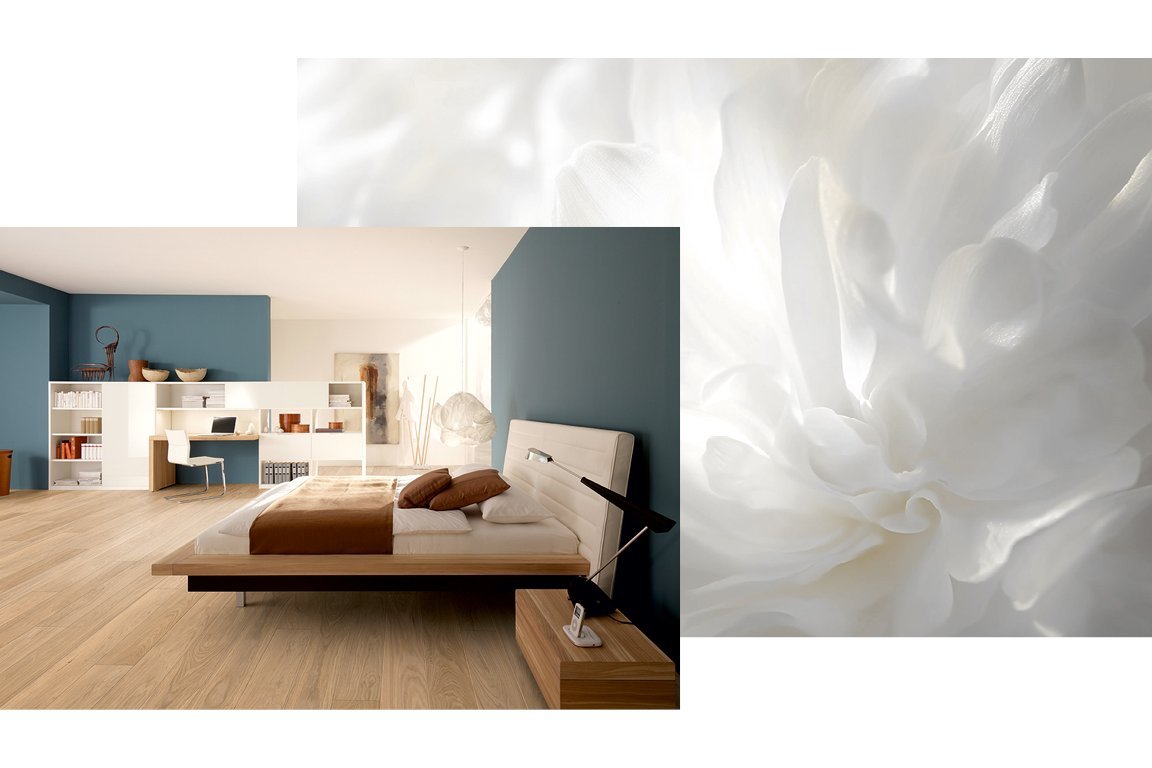 Schlafzimmer mit hellem Eichenparkett in Cloud-Dancer-Tönen, blaugrauen Wänden, Wolken-Deckenleuchte sowie Holzbett und Schreibtisch.