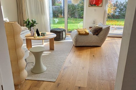 Helles Skandi-Wohnzimmer mit Landhausdiele Eiche und großen Fenstern.