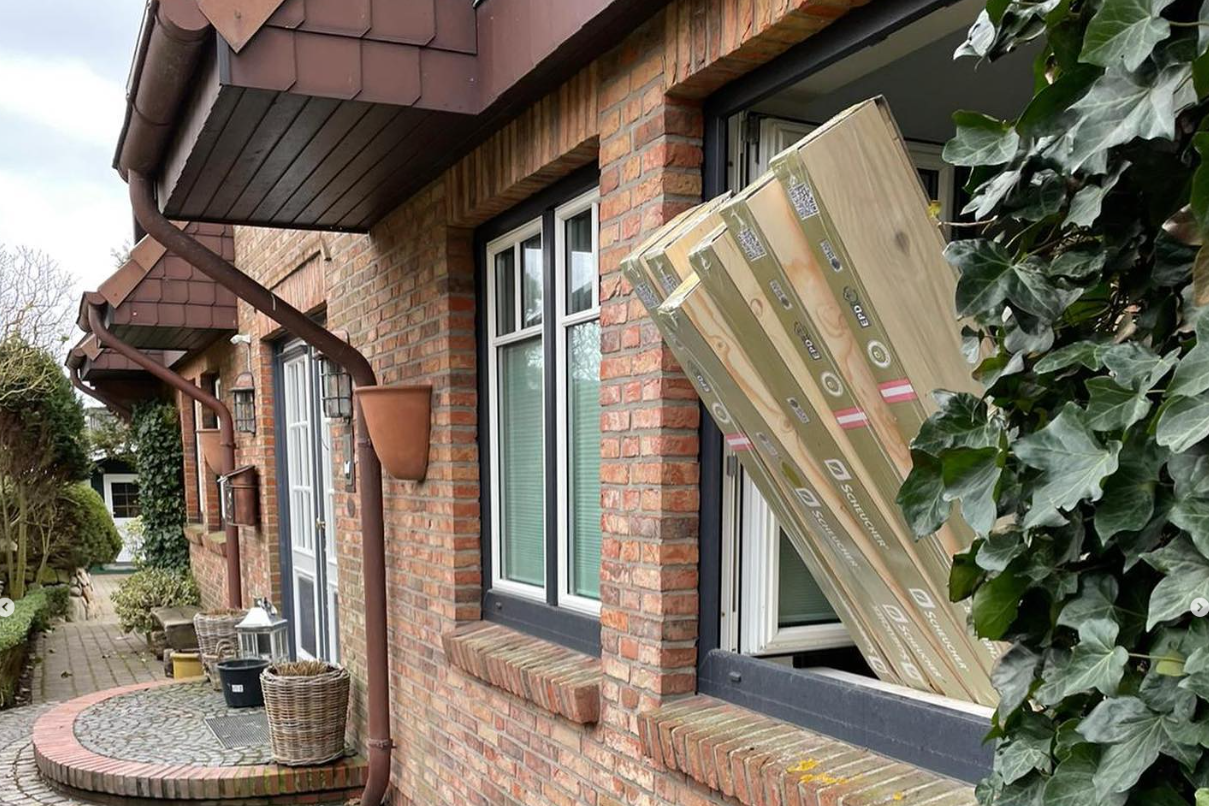 Friesisches Haus in Renovierung. Aus dem Fenster ragen Pakete mit Parkett, das bald verlegt wird.