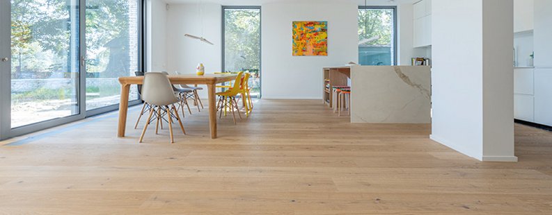 Offenes Esszimmer und Küche mit Landhausdielen aus weißer Eiche, kombiniert mit Marmorflächen und bunten Möbel-Highlights.