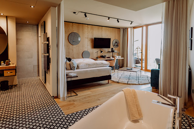 [Translate to EN:] Modernes Hotelzimmer mit Holzboden und Fliesen
